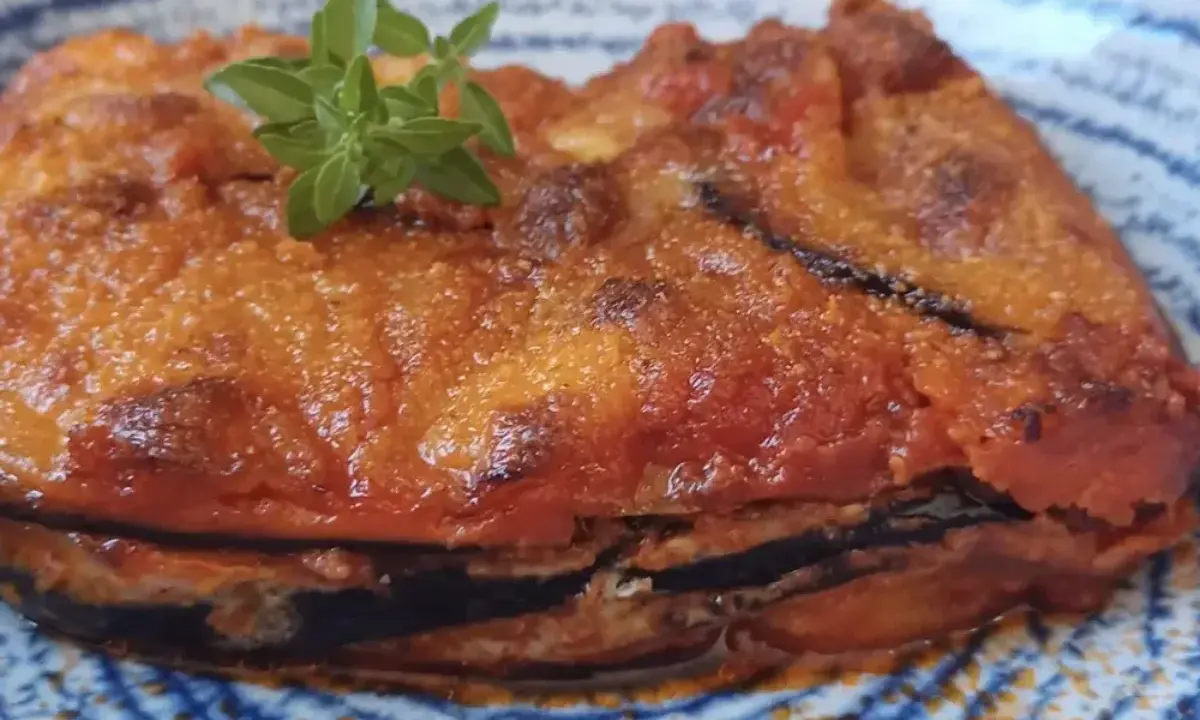 Parmigiana in padella, uno strato di melanzane fritte, pomodoro e formaggio, guarnita con basilico fresco.