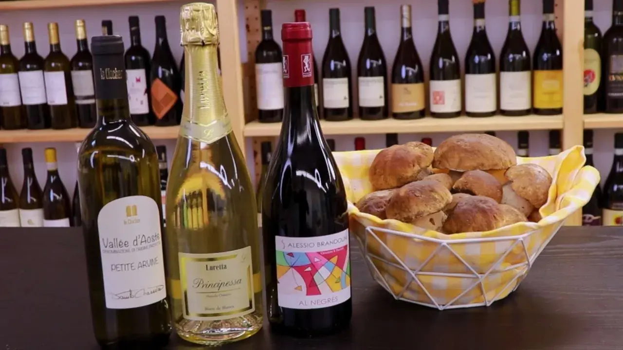 Vino da abbinare ai funghi: una bottiglia di rosso e due spumanti con un cesto di funghi porcini freschi.