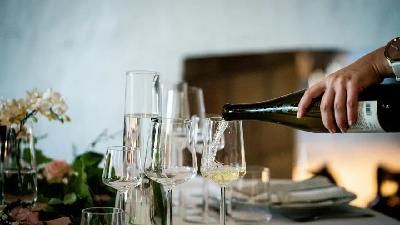 Versando vino bianco in un calice, un assaggio dei profumi dei vitigni siciliani.