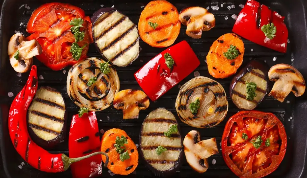 Grigliata di giugno con verdure di stagione: pomodori, melanzane, peperoni, cipolle, carote e funghi, guarnite con prezzemolo.
