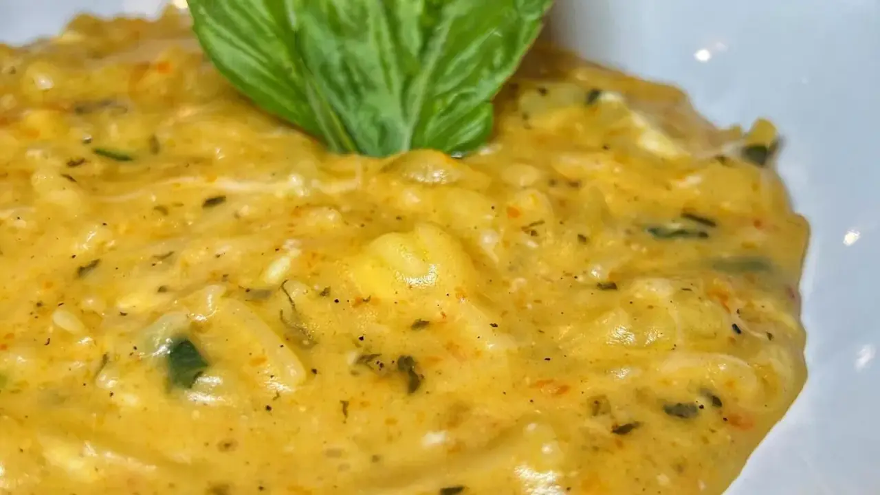 Un cremoso piatto di pasta patate e provola, arricchito da erbe aromatiche e guarnito con una foglia di basilico fresco.