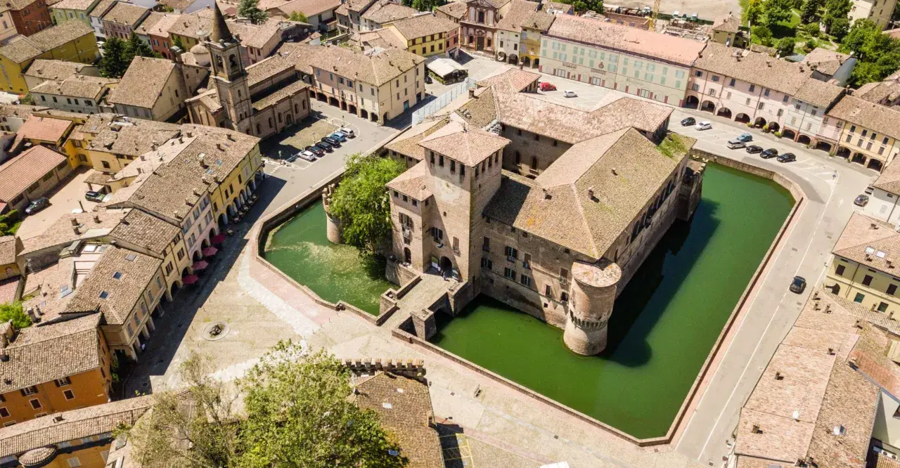 Castello con fossato e borgo storico. Un'idea di cosa vedere a Parma in un giorno, tra torri e tetti rossi.