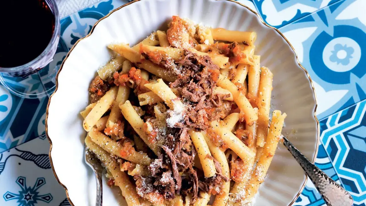 Un piatto invitante di pasta alla genovese, con maccheroni conditi con un ricco ragù di carne e spolverata di parmigiano.