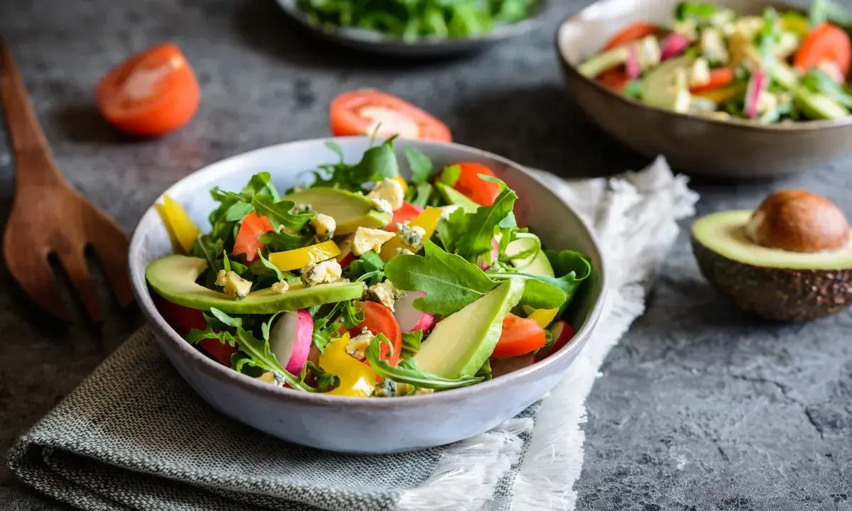 Insalata fresca con avocado, pomodorini, rucola e formaggio blu. Un piatto colorato e salutare.