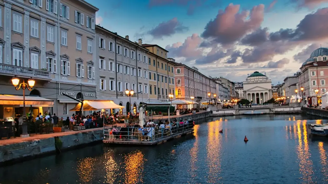 Canale di Trieste al tramonto, con ristoranti sul lungomare e riflessi dorati sull'acqua. Un'ottima idea per una delle città da visitare in un giorno.