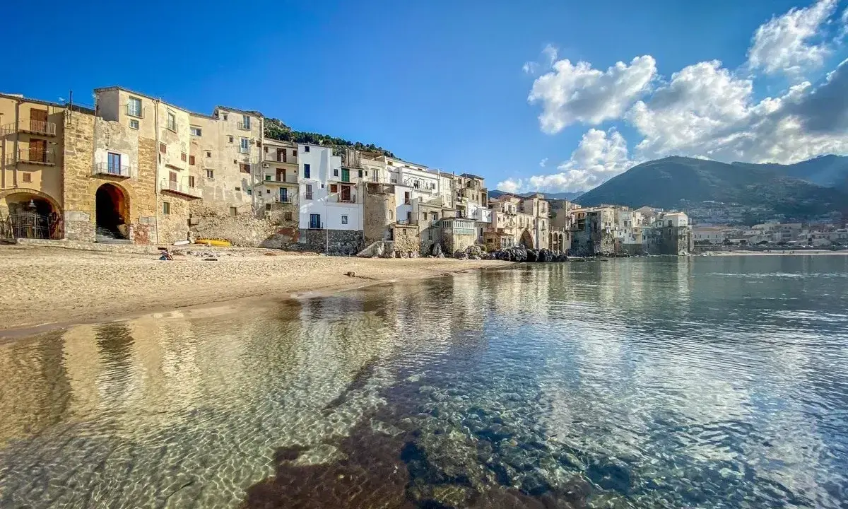 Cefalù, un gioiello da scoprire vicino a Palermo. Case colorate affacciate su una spiaggia dorata e un mare cristallino.