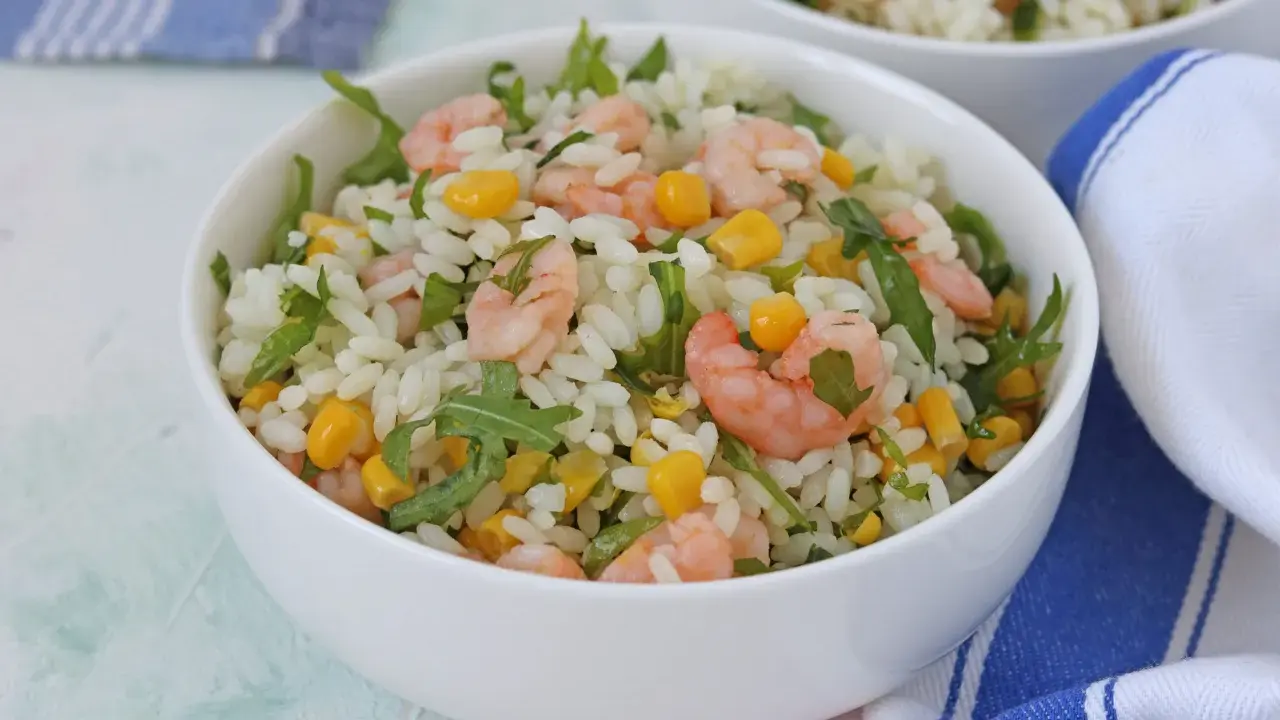 Insalata di riso con gamberetti, mais e rucola, un piatto fresco e colorato, servito in una ciotola bianca.