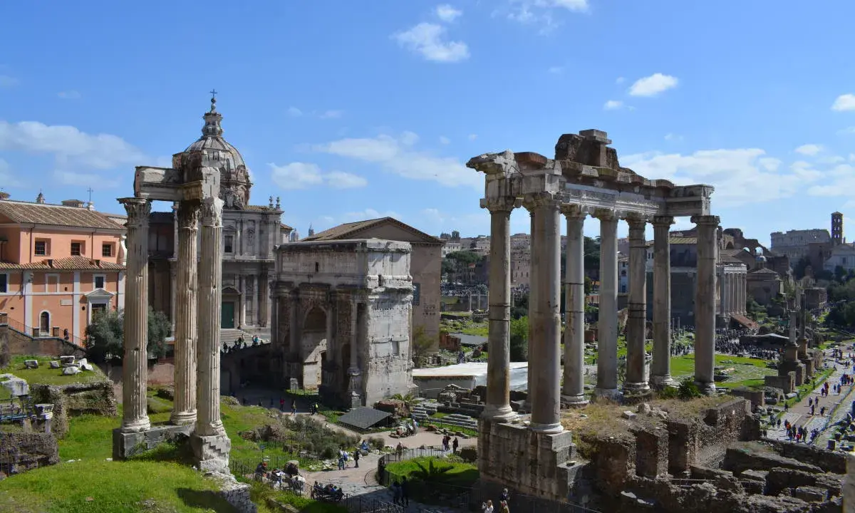 Antiche rovine romane, un arco trionfale e una chiesa con cupola, ideali per scoprire cosa fare a Roma nel weekend.