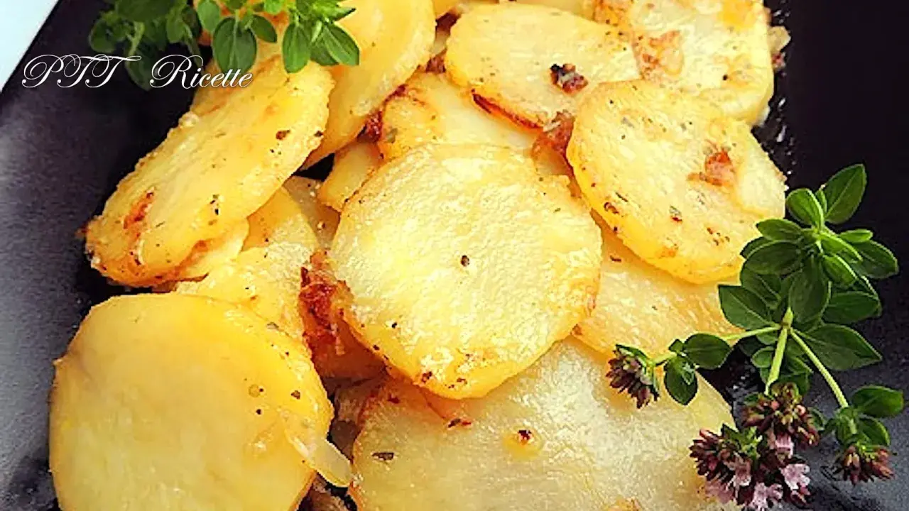 Patate e cipolle in padella, dorate e profumate, guarnite con rametti di origano fresco.