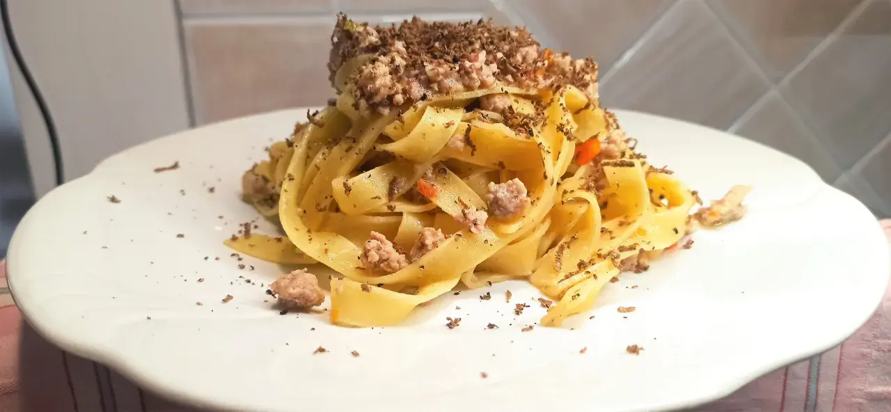Tagliatelle al ragù con scaglie di tartufo nero, un piatto ricco e profumato, pronto per essere gustato.