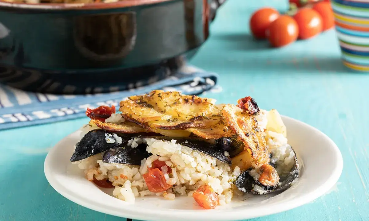 Piatto di riso patate e cozze, ricetta originale pugliese, con pomodorini e patate dorate in forno.