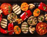 Grigliata di giugno con verdure di stagione: pomodori, melanzane, peperoni, cipolle, carote e funghi, guarnite con prezzemolo.