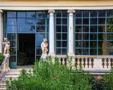 Statue di nani custodi di un giardino lussureggiante sui Colli Berici, con un'elegante serra sullo sfondo.