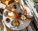 Un tagliere con formaggi, salumi e marmellata, accompagnato da un bicchiere di vino rosso. Le caratteristiche del nebbiolo vino si esaltano con questi sapori.