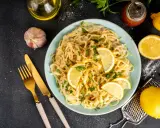 Spaghetti cremosi con un profumo agrumato, guarniti con fette di limone fresco e prezzemolo. Un piatto di pesto al limone che invita a gustare la freschezza.