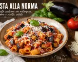 Piatto di pasta con sugo alla norma, ricco di melanzane fritte, pomodoro e ricotta salata grattugiata, guarnito con basilico fresco.