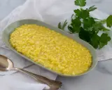 Un cremoso risotto al pistacchio, servito in un piatto ovale con un cucchiaio d'argento e un rametto di prezzemolo fresco.