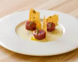 Tre cilindri di tartare di manzo, guarniti con timo, su una crema chiara e croccanti cialde. Un'idea su come condirla.