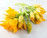 Mazzi di fiori di zucca freschi, gialli e vibranti, legati con spago bianco. Perfetti per imparare come conservare i fiori di zucca.