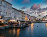 Canale di Trieste al tramonto, con ristoranti sul lungomare e riflessi dorati sull'acqua. Un'ottima idea per una delle città da visitare in un giorno.