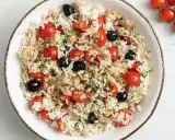 Insalata di riso con tonno, pomodorini, olive nere e prezzemolo. Un'idea fresca e gustosa su come condire l'insalata di riso per un pranzo estivo.