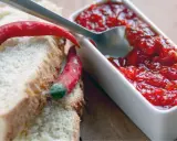 Fette di pane con peperoncini rossi e una ciotolina di marmellata di peperoncino, pronta per essere gustata.