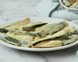 Zucchine fritte in pastella dorata, croccanti e invitanti, servite su un piatto bianco.