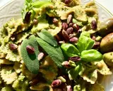 Farfalle condite con un saporito pesto di salvia, guarnite con pistacchi, basilico e olive verdi.