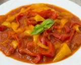 Peperonata ricetta della nonna: peperoni rossi e gialli cotti lentamente in un sugo saporito, guarniti con basilico fresco.