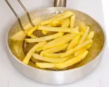 Patate fritte dorate che sfrigolano nell'olio bollente, pronte per essere gustate.