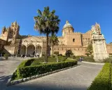 Il percorso per Palermo inizia con la maestosa Cattedrale, tra palme e giardini curati, sotto un cielo azzurro.