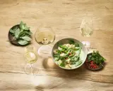 Un curry verde con gamberi e verdure, accompagnato da bicchieri di vino bianco, evoca le fresche **sauvignon blanc caratteristiche**.