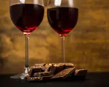 Due calici di vino rosso e una pila di cioccolato fondente, un perfetto abbinamento vino e cioccolato per un momento di piacere.