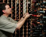 Uomo in cantina sceglie una bottiglia, pensando se il suo chardonnay è fermo o frizzante.