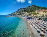 Spiaggia affollata con ombrelloni e gente che nuota in acque cristalline. Un'idea perfetta per decidere dove andare un weekend in Italia.