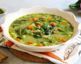 Un fumante minestrone genovese, ricco di verdure fresche, piselli, carote e fagioli, servito con pesto e pane tostato.