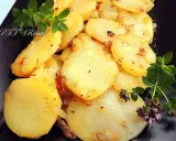 Patate e cipolle in padella, dorate e profumate, guarnite con rametti di origano fresco.