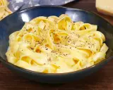 Un piatto di fettuccine alfredo fumanti, condite con una cremosa salsa al parmigiano e pepe nero.