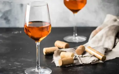 Calici di vino arancione, un'introduzione a cosa sono questi vini unici. Tappi e cavatappi completano la scena.