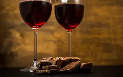 Due calici di vino rosso e una pila di cioccolato fondente, un perfetto abbinamento vino e cioccolato per un momento di piacere.