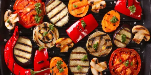 Grigliata di giugno con verdure di stagione: pomodori, melanzane, peperoni, cipolle, carote e funghi, guarnite con prezzemolo.