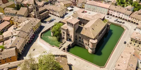 Castello con fossato e borgo storico. Un'idea di cosa vedere a Parma in un giorno, tra torri e tetti rossi.
