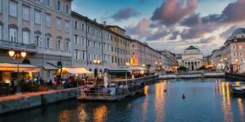 Canale di Trieste al tramonto, con ristoranti sul lungomare e riflessi dorati sull'acqua. Un'ottima idea per una delle città da visitare in un giorno.