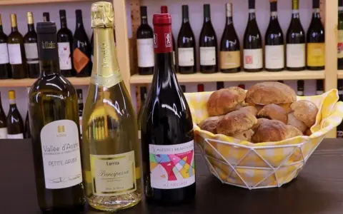Vino da abbinare ai funghi: una bottiglia di rosso e due spumanti con un cesto di funghi porcini freschi.