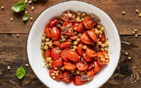 Insalata di ceci e pomodorini, un'idea fresca per le tue ricette con farina di ceci. Guarnita con pinoli e acciughe.