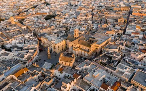 Nardò, dove si trova questo centro storico con chiese barocche e tetti bianchi, illuminato dalla luce dorata del tramonto.
