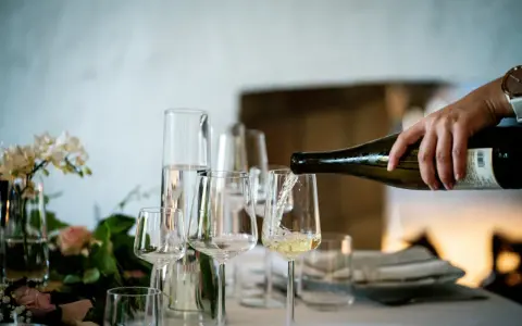 Versando vino bianco in un calice, un assaggio dei profumi dei vitigni siciliani.