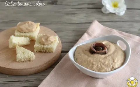 Salsa tonnata con maionese, cremosa e gustosa, servita su cubetti di pane e in una ciotola con acciughe.