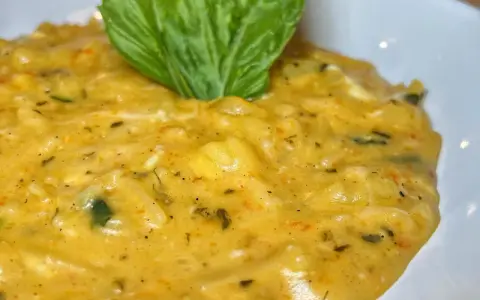 Un cremoso piatto di pasta patate e provola, arricchito da erbe aromatiche e guarnito con una foglia di basilico fresco.