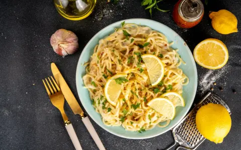 Spaghetti cremosi con un profumo agrumato, guarniti con fette di limone fresco e prezzemolo. Un piatto di pesto al limone che invita a gustare la freschezza.